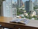 City view from high-rise apartment with desk and book