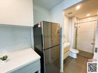 Compact bathroom with integrated laundry space including a washing machine next to a shower cubicle