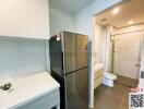 Compact bathroom with integrated laundry space including a washing machine next to a shower cubicle