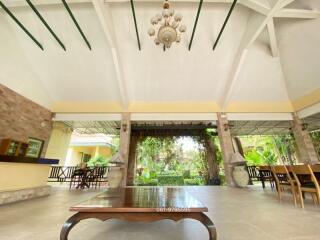 Spacious covered patio with elegant ceiling design, natural stone walls, and garden view