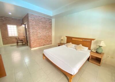 Spacious bedroom with a queen-sized bed, brick accent wall, and ample natural light.