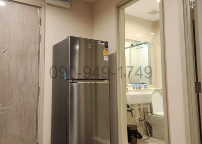 Compact kitchen with stainless steel refrigerator and adjacent bathroom