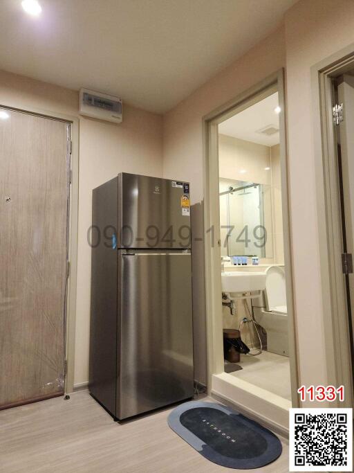 Compact kitchen with stainless steel refrigerator and adjacent bathroom