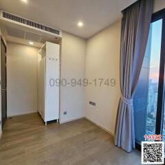 Spacious and well-lit bedroom with wooden flooring and city view through the window