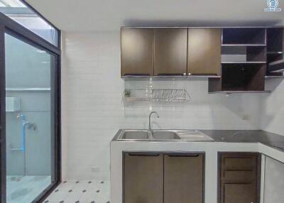 Modern kitchen with stainless steel sink, wooden cabinets, and tiled flooring