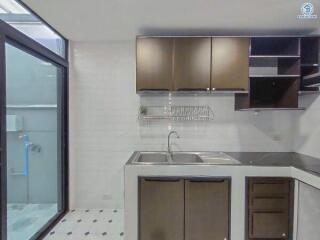 Modern kitchen with stainless steel sink, wooden cabinets, and tiled flooring