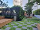 Modern outdoor common space with green landscaping, benches, and walking paths between apartment buildings