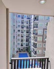 View from a balcony overlooking a residential building with a swimming pool