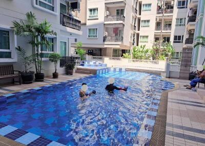 Residents enjoying a sunny day at the communal swimming pool surrounded by apartment buildings