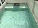 Private swimming pool with green tiles surrounded by a white deck area