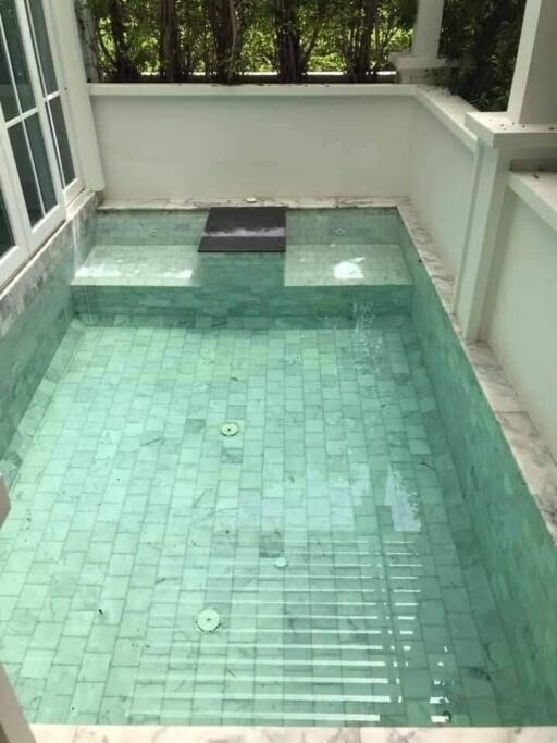 Private swimming pool with green tiles surrounded by a white deck area