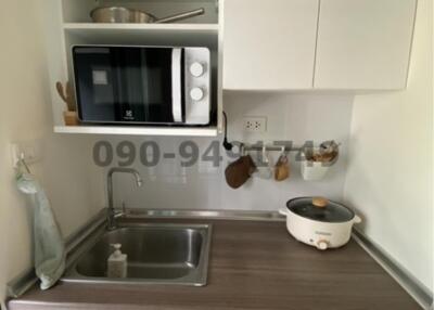 Compact kitchen area with modern appliances and white storage cabinets