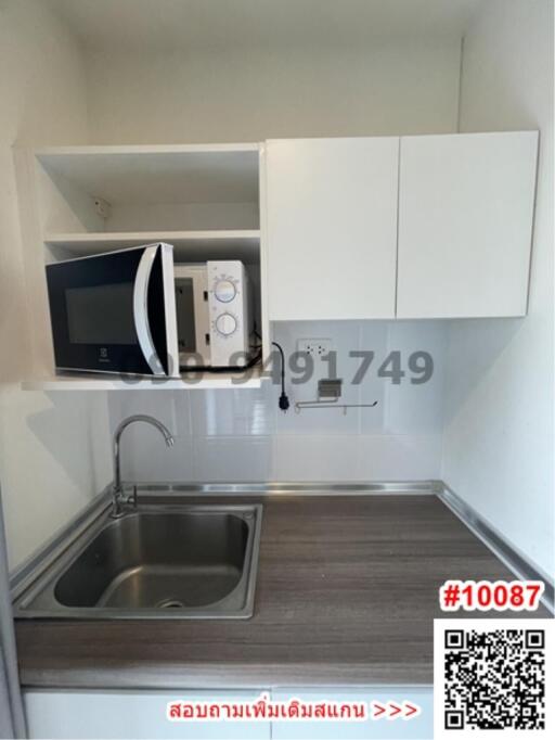 Compact modern kitchen with stainless steel sink, microwave, and white cabinets