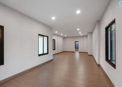 Spacious empty room with wooden flooring and multiple windows