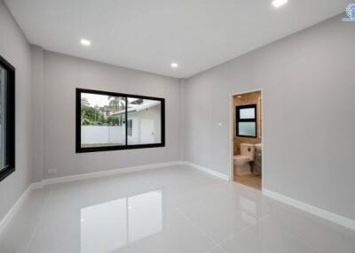 Spacious modern bedroom with glossy floor, large windows, and en suite bathroom