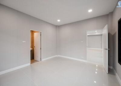Spacious empty bedroom with white walls and glossy tiled flooring