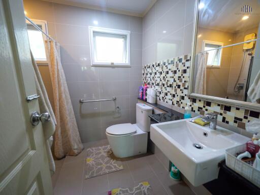 Spacious bathroom with modern tiling, bathtub, and window