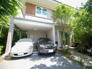 Exterior view of a two-story house with carport and vehicles