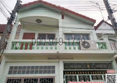 Exterior view of a two-story house with balcony and gated entrance