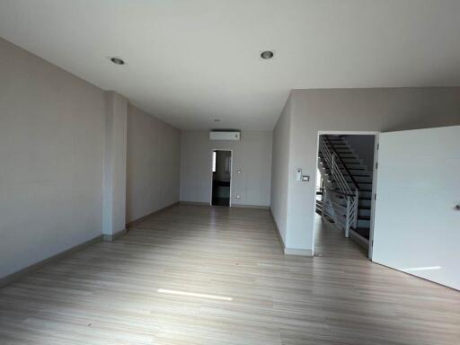 Spacious and well-lit empty living room with wooden flooring and staircase
