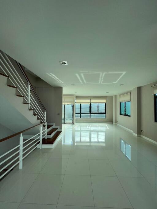 Spacious and bright living room with glossy tiled flooring and staircase