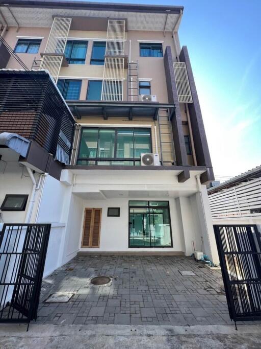 Modern three-story residential building facade with a balcony and garage space