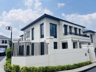 Modern two-story house with a white exterior, balustrades, and landscaped front yard