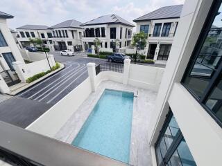 View from balcony overlooking a private pool and the street in a residential area