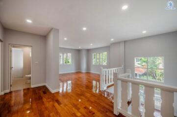Spacious and well-lit living area with polished hardwood floors and modern lighting