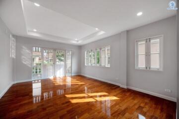 Spacious and bright living room with hardwood floors and multiple windows