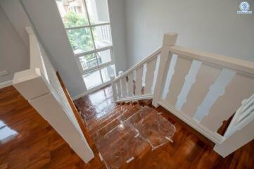 Bright staircase with wooden floors and white railing