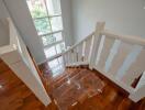 Bright staircase with wooden floors and white railing