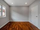 Empty bedroom interior with hardwood floors and natural light