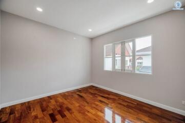 Spacious unfurnished bedroom with polished hardwood floor and ample natural light