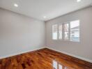 Spacious unfurnished bedroom with polished hardwood floor and ample natural light