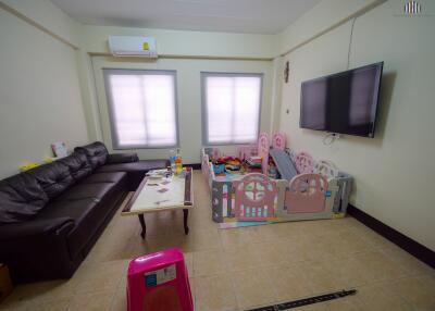 Spacious living room with natural light, modern furnishings, and a dedicated play area for children