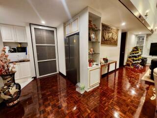Spacious living room with polished hardwood floors, modern kitchen area, and Christmas decorations