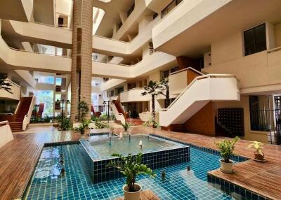 Luxurious indoor swimming pool with a grand staircase and surrounding apartment balconies