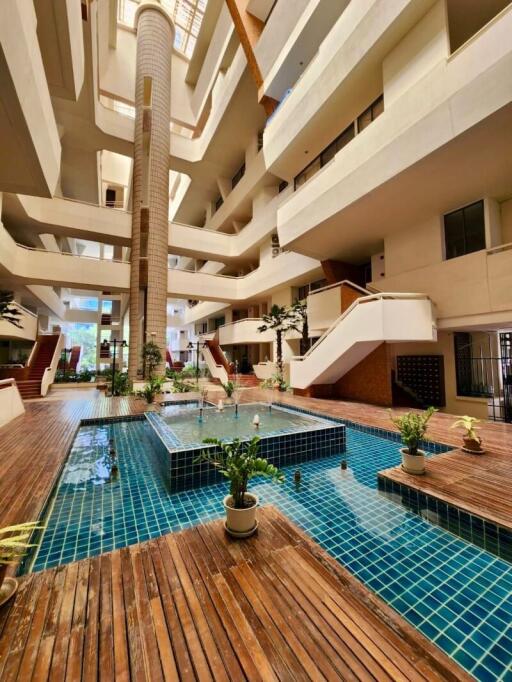 Luxurious indoor swimming pool with a grand staircase and surrounding apartment balconies