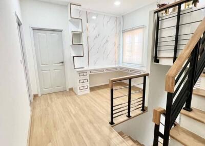 Modern staircase area with white walls, wooden floors, and natural light