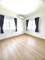 Spacious and well-lit bedroom with hardwood flooring and air conditioning