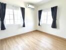 Spacious and well-lit bedroom with hardwood flooring and air conditioning