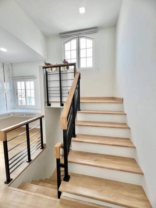 Modern staircase with wooden steps and black metallic railing