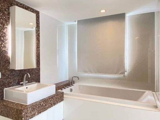 Modern bathroom with mosaic tile backsplash and a large bathtub