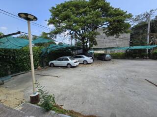 Spacious outdoor parking space with covered areas and mature trees