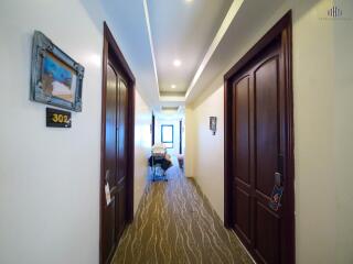 Brightly lit hallway in a residential property with multiple wooden doors and carpeted floor