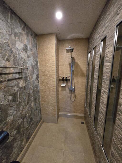 Spacious modern bathroom with walk-in shower and textured tile walls