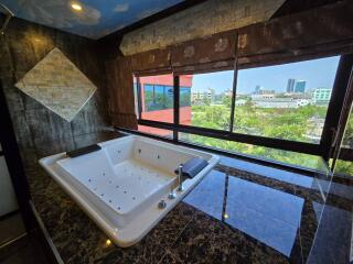 Spacious bathroom with a large jacuzzi tub, marble flooring, and a city view