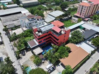 Aerial view of a red multi-story building with surrounding greenery