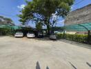 Spacious outdoor parking area with vehicles and shade trees